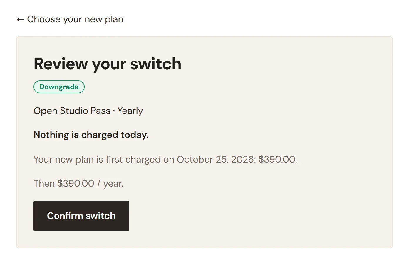 The Review your switch page, labeled Downgrade, for Open Studio Pass Yearly, saying Nothing is charged today, that the new plan is first charged on October 25, 2026 for $390.00, then $390.00 / year, with a Confirm switch button